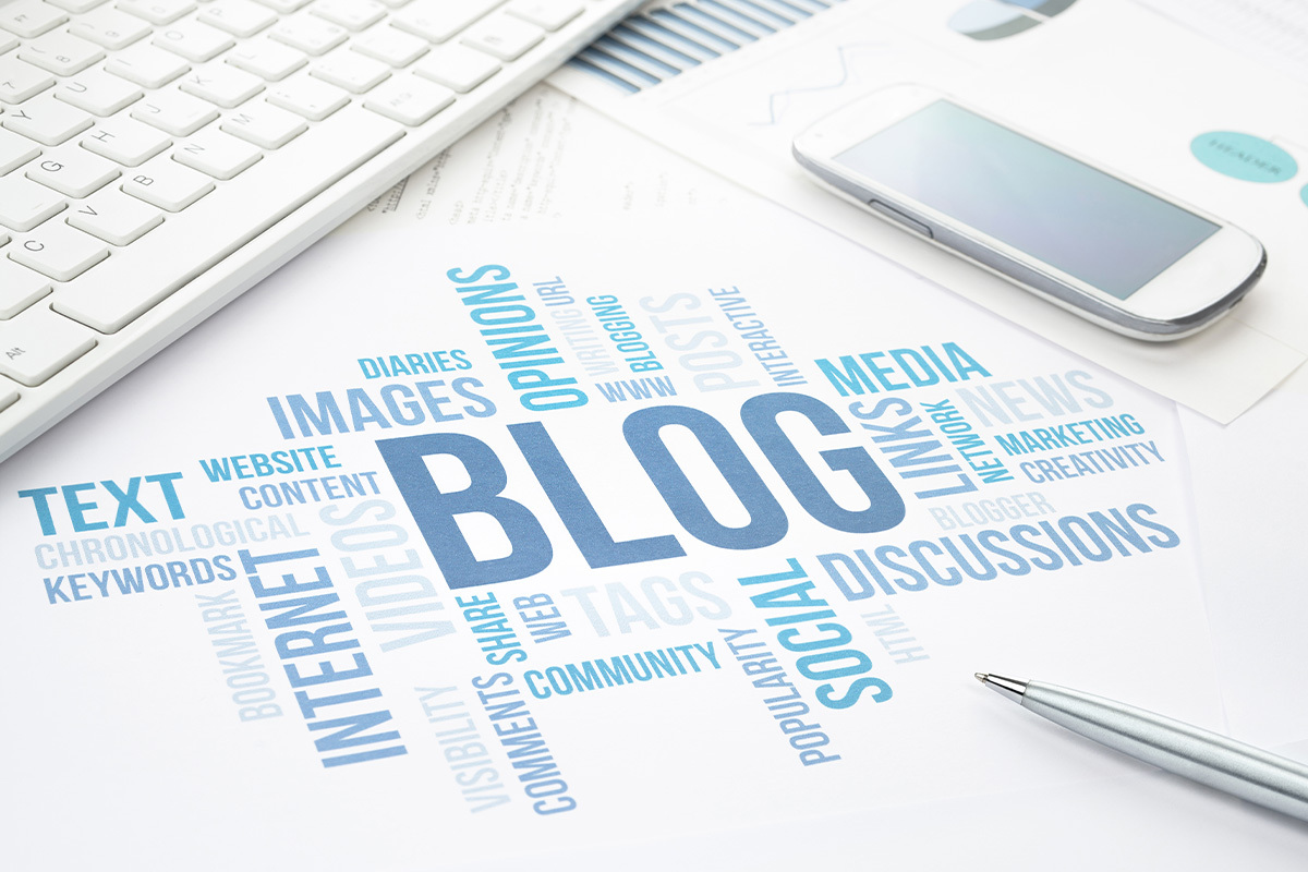 blog-aziendale-come-asset-strategico Blog aziendale come asset strategico. Nell'immagine presenti in orizzontale e verticale tutte le parole che possono far parte di questo asset: il blog aziendale. Come se fossero sciritte su di una scrivania dove sono presenti tastiera e smartphone.